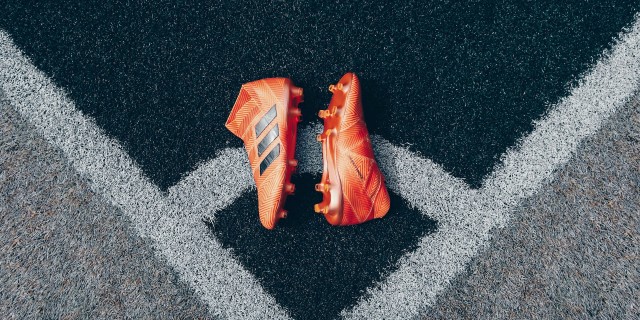 Orange football boots on gray astroturf
